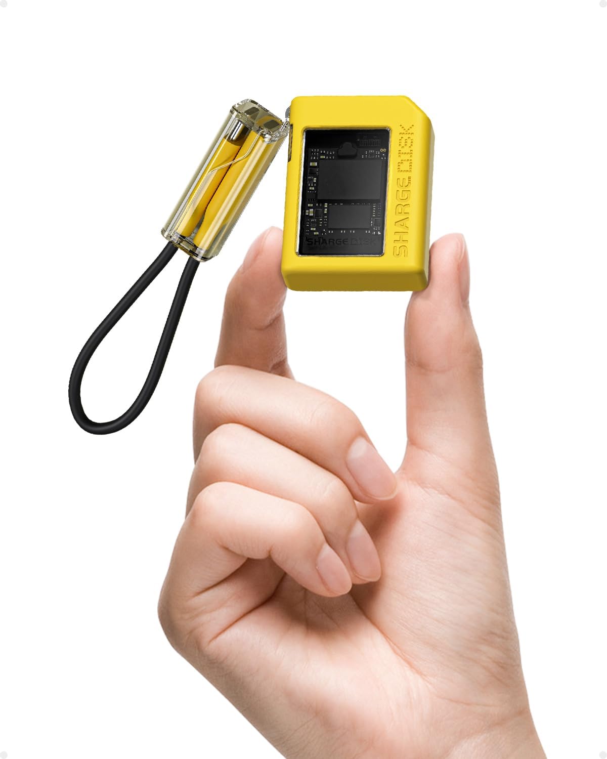 Yellow SHARGE Disk with a clear window over the drive inside, held between two fingers, its short looped cable hanging beside it