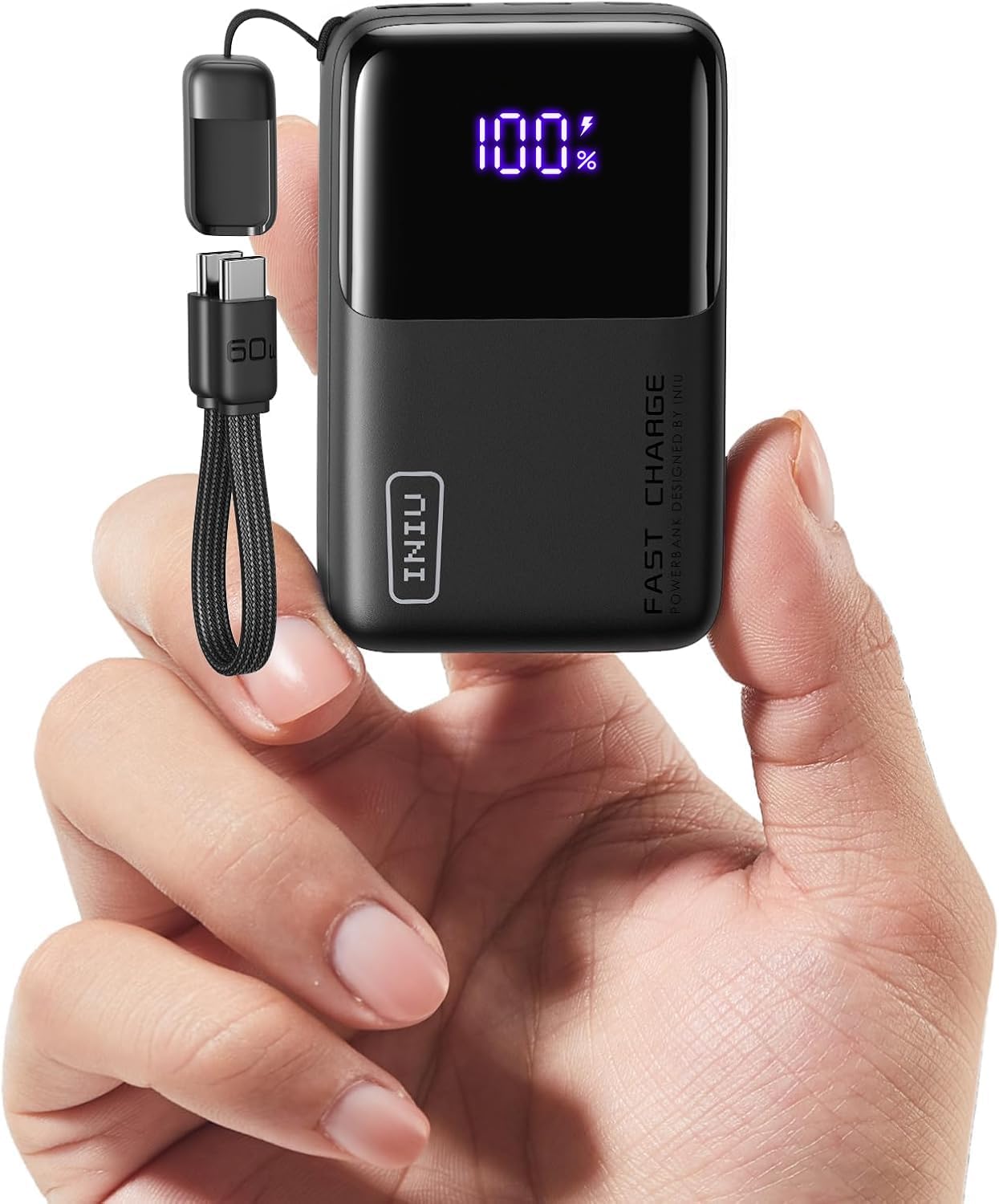 Black INIU power bank held between a thumb and two fingers, its display reading 100%, FAST CHARGE printed down its front and a short braided USB-C cable looped from its top corner