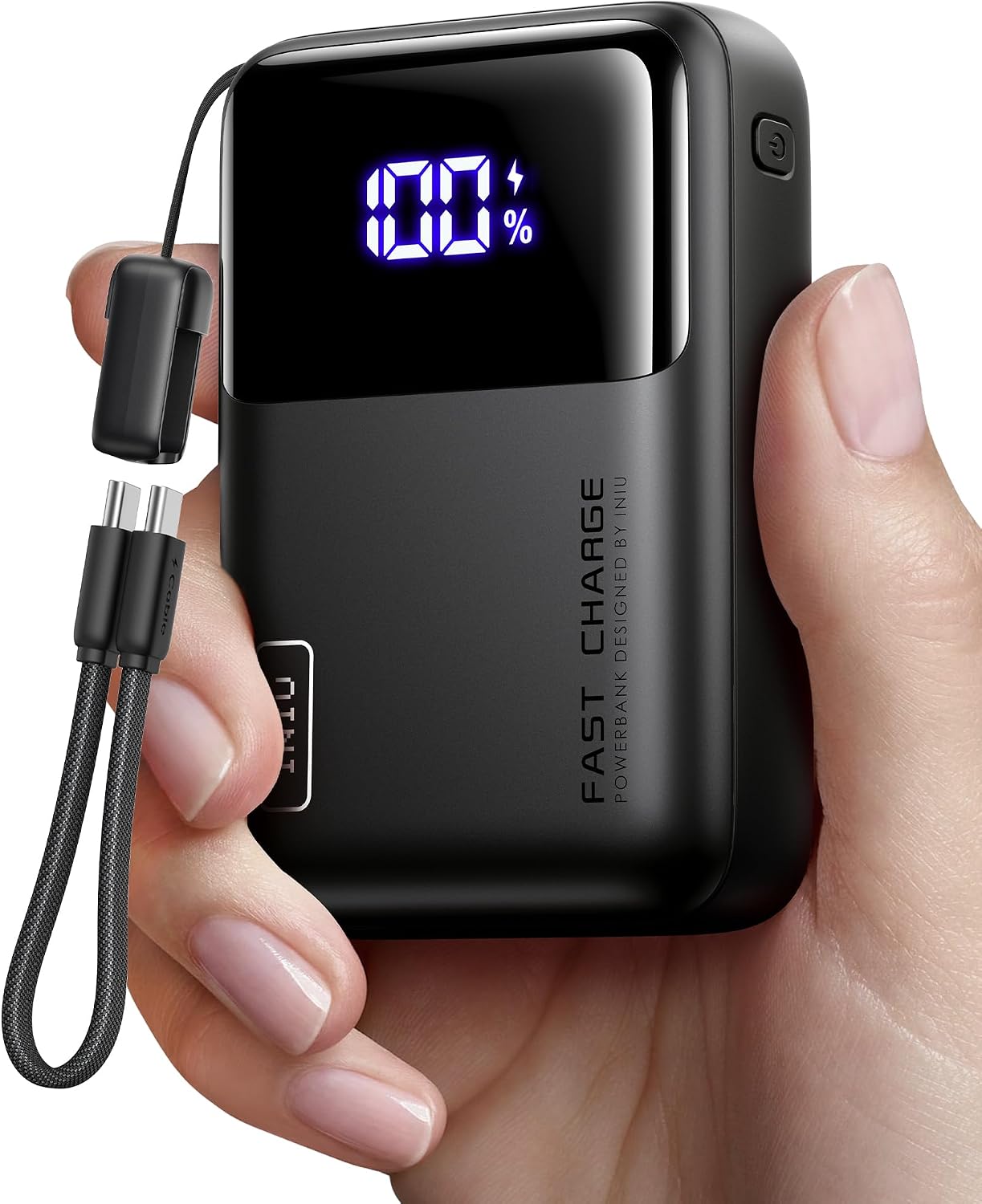 Black INIU power bank in a hand, its display reading 100%, a button on its right edge, FAST CHARGE printed down its front and a short braided USB-C cable looped from its top