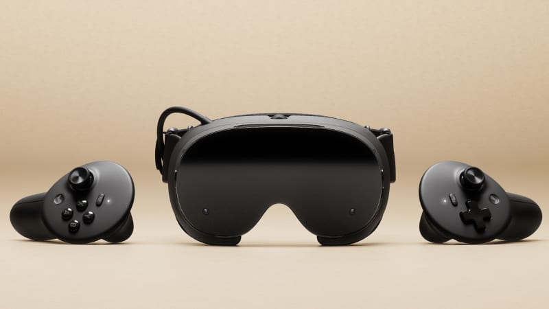 The black Valve Steam Frame headset seen from the front, between its two controllers, on a beige background